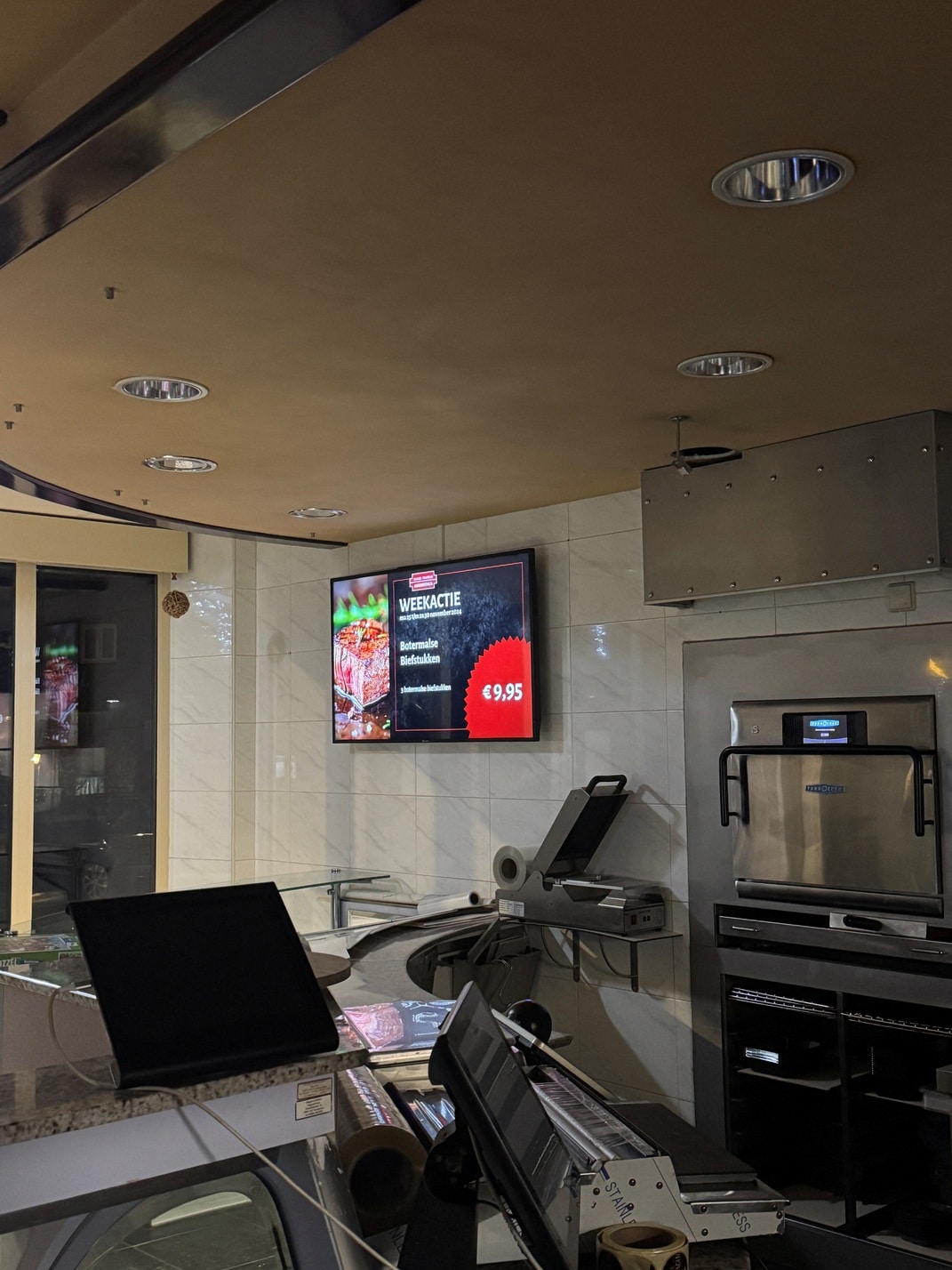 Portrait display in de etalage van Slagerij Augustinus met narrowcasting content en weekaanbiedingen
